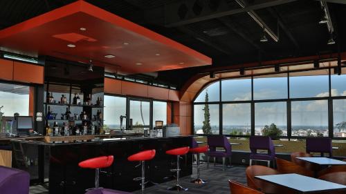 a restaurant with a bar with red chairs and windows at Aston Jambi Hotel & Conference Center in Jambi
