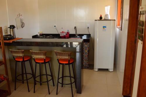 a kitchen with a bar with stools and a refrigerator at Pousada dos Sonhos in Barra