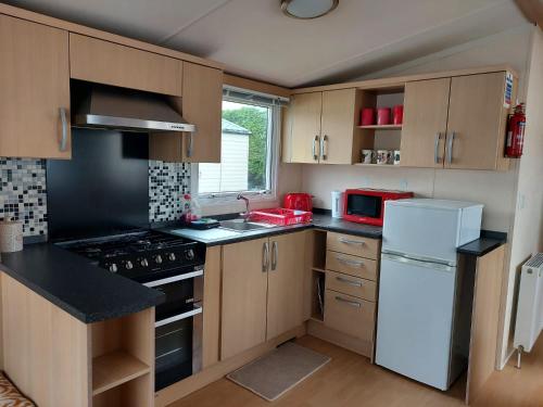 a kitchen with wooden cabinets and a white refrigerator at 6 berth pet friendly caravan on Sandy Glade (John Fowlers) Brean in Berrow