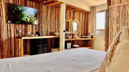 1 dormitorio con 1 cama y TV en la pared en Orchid Beach House Adults Only, en Tulum