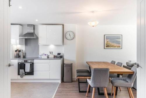 a kitchen and dining room with a table and chairs at Beach Mews - Modern townhouse with patio and private parking in Kent