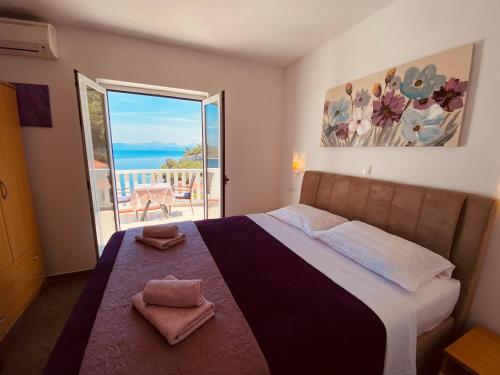 a bedroom with a bed with a view of the ocean at Guest House Ruža in Sobra