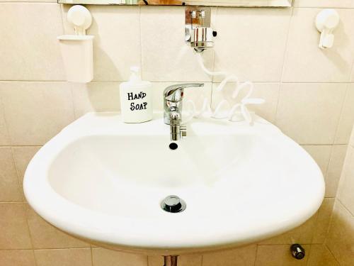 a white sink in a bathroom with a had sign on it at La Casetta di San Giovanni in Rome