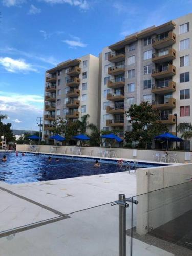 a swimming pool with blue umbrellas in front of buildings at Alojamiento en Apartamento en Ricaurte in Ricaurte