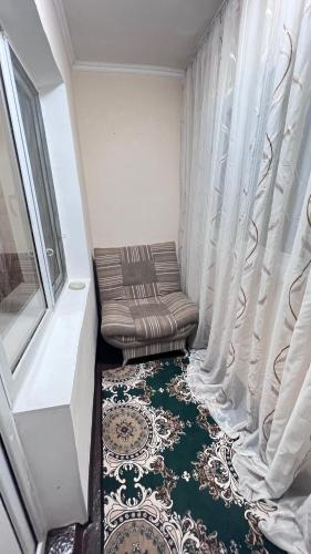 Cette petite chambre comprend une chaise et une fenêtre. dans l'établissement Чистая и уютная квартира в 6-ом микрорайоне, à Taraz