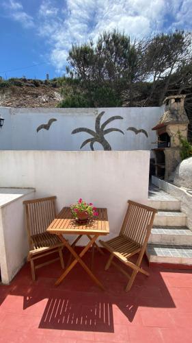 a wooden table and two chairs on a patio at Apartamento Miradouro in Carrapateira