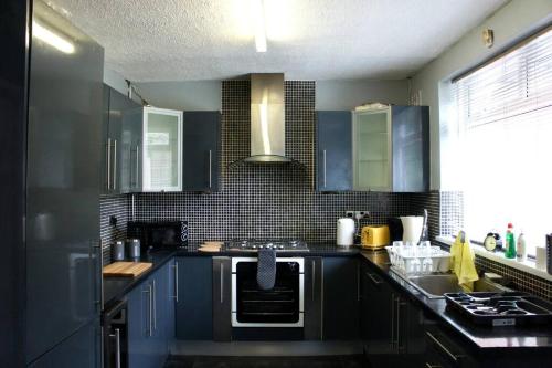 曼徹斯特的住宿－Swinton, Manchester，厨房配有蓝色橱柜和水槽