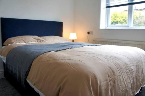 a bedroom with a bed with a blue headboard and a window at Swinton, Manchester in Manchester