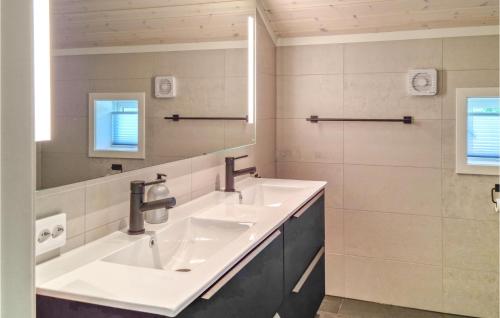 a bathroom with two sinks and a mirror at Nice Home In Frvik With Wifi, 3 Bedrooms And Outdoor Swimming Pool in Færvik