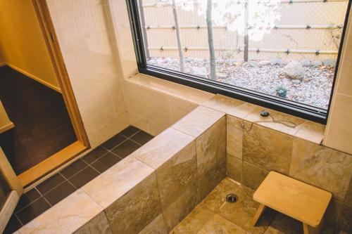 a bathroom with a shower with a window and a stool at WASEIDOU ZEN - Vacation STAY 19522v in Kobe