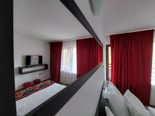 a room with two beds and red curtains at Casa Nico Nelu Duplex in Arieşeni