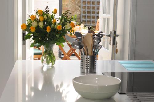 una mesa con un jarrón de flores y un tazón en ella en Serendipity en Kirkcudbright