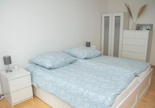 a white bedroom with a bed and a dresser at Apartment am Kurpark in Bad Segeberg