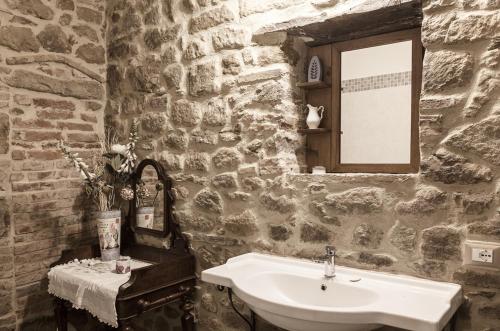 Baño de piedra con lavabo y espejo en La Villa Del Cedro, en Ciggiano