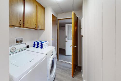 a laundry room with a washing machine and a hallway at Lazy Dayz Cottage in Christina Lake