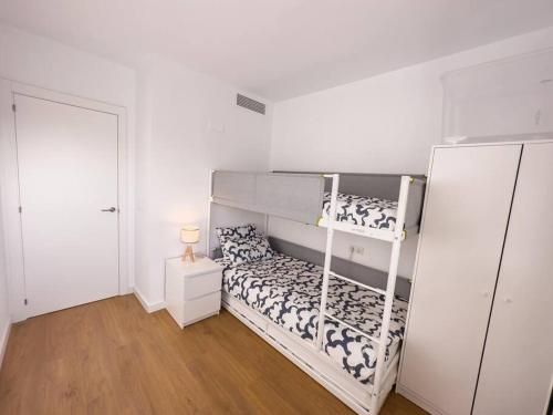 ein weißes Schlafzimmer mit einem Etagenbett und einer Tür in der Unterkunft Tranquilidad a 2 minutos del mar in Canet d'en Berenguer