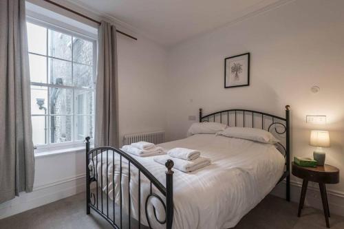 a bedroom with a bed with white sheets and a window at Jane's View - Luxury apartment with breathtaking views in Kent