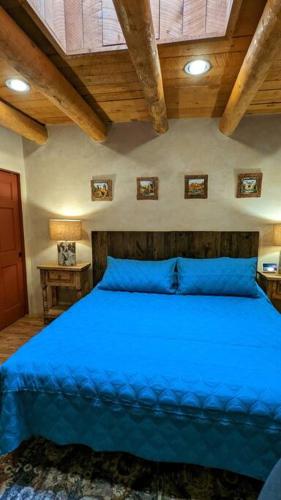 a blue bed in a bedroom with wooden ceilings at Enchanted Casita with Private Outdoor Hot Tub and Patio, Near Santa Fe Plaza, Sleeps 4 with free parking in Santa Fe