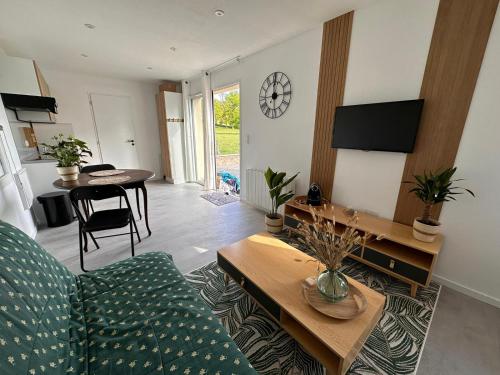 uma sala de estar com um sofá e uma mesa em Tiny House moderne et son jardin privé - 5mn Roanne 