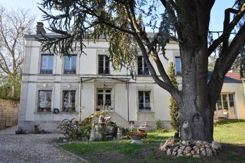 une maison blanche avec un arbre en face dans l'établissement CLOS REMY Maison d'hôtes, à Précy-sur-Oise