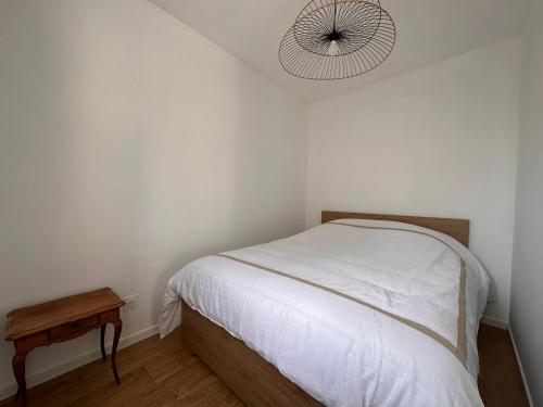 um quarto com uma cama branca e uma mesa de madeira em Tiny House moderne et son jardin privé - 5mn Roanne 
