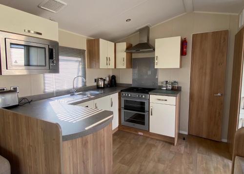 a kitchen with white cabinets and a stove top oven at Beach Caravan Holiday Home in Mablethorpe