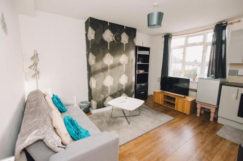 a living room with a couch and a tv at Luxury Central Luton - King-size Apartment - Free Parking - Free Wi-Fi - Near Shops & LTN Airport in Luton