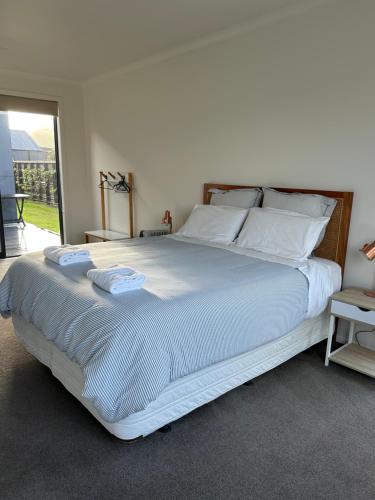 a bedroom with a large bed with white sheets and pillows at Purangi Beachhouse in Cooks Beach