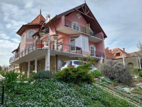 a pink house with a car parked in front of it at Manor Villa in Hévíz