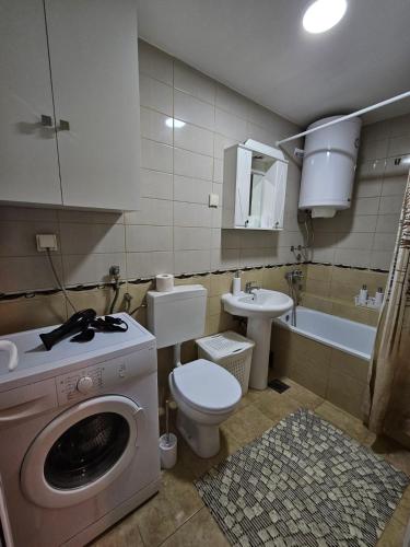 ein Badezimmer mit einer Waschmaschine, einem WC und einem Waschbecken in der Unterkunft Duca apartmani in Šabac