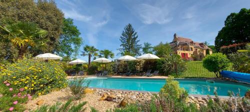 uma piscina em frente a uma casa com guarda-sóis em Gîte Les Pierres Blondes em Groléjac