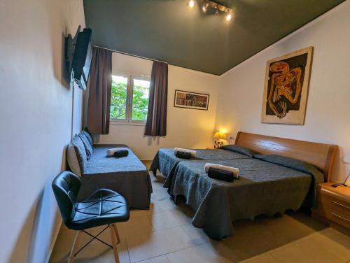 1 dormitorio con 2 camas, silla y ventana en Dalt Vila Salou, en Salou