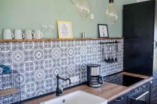 a kitchen with a sink and a tile wall at Meerblick und Salz in der Luft in Fehmarn