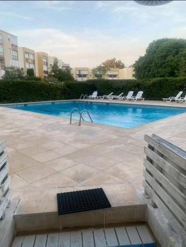 une piscine avec des chaises longues dans un immeuble dans l'établissement Appartement avec piscine et garage, au Grau-du-Roi