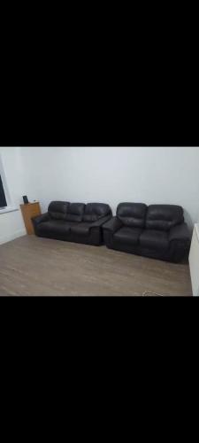 two black leather couches sitting in a living room at Double room in Lees