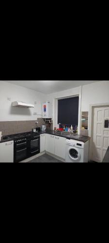 een keuken met zwart-witte apparatuur en een raam bij Double room in Lees