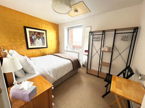Schlafzimmer mit einem Bett, einem Schreibtisch und einem Fenster in der Unterkunft GOLD Penthouse Room 5min to Basingstoke Hospital in Basingstoke