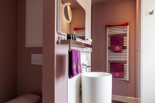 a bathroom with a white sink and purple towels at Saint Georges Bruges Luxury Suites in Bruges