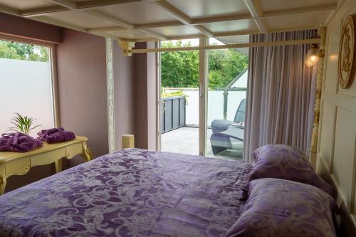 a bedroom with a purple bed and a balcony at Saint Georges Bruges Luxury Suites in Bruges
