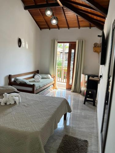 a bedroom with two beds and a balcony with a piano at Pousada Luz da Lua in Búzios