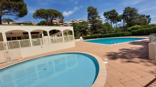 deux piscines dans une cour avec des arbres et un bâtiment dans l'établissement Charmant Appartement résidentiel avec Terrasse, Jardin Privatif et Piscine à Cannes, à Cannes