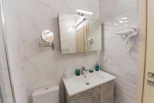 a white bathroom with a sink and a mirror at Athina Pantheon Mitropoleos in Thessaloniki