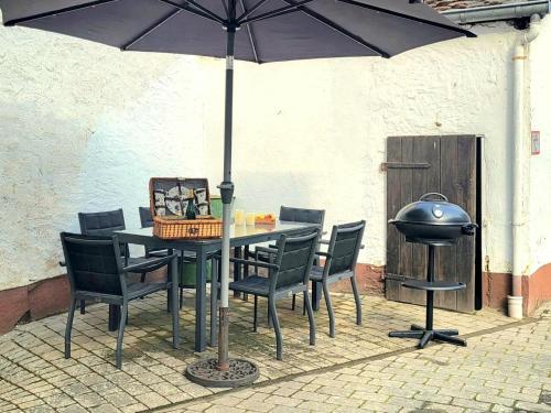 a table and chairs with an umbrella and a grill at Haus zur Heugabel in Kesten