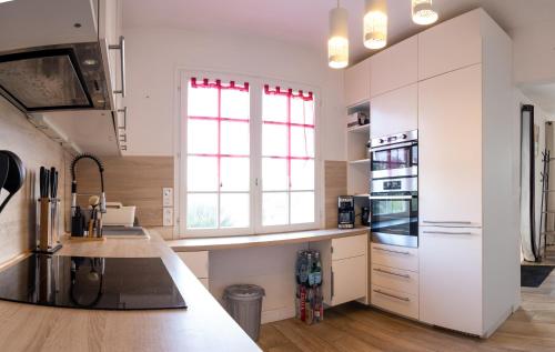 une cuisine avec des placards blancs et une grande fenêtre dans l'établissement Belle villa à 150m de la plage., à Locquirec