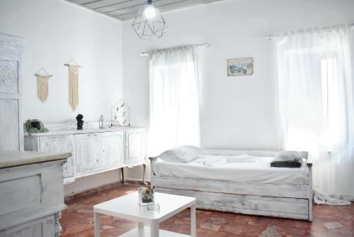 a white bedroom with a bed and a table at Giagia Annousio in Dhriopís