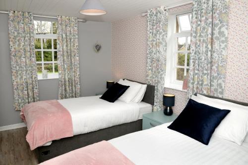 two beds in a room with windows and curtains at Cloverhill Gate Lodge in Cloverhill