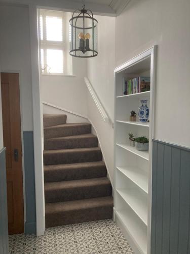 a staircase in a home with a chandelier at Serendipity in Kirkcudbright