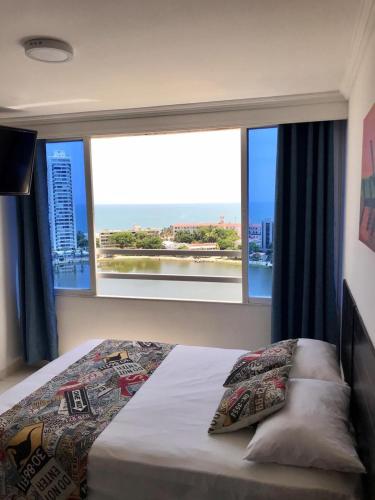 um quarto com uma cama e uma grande janela em Apartamento totalmente equipado a media cuadra de la playa del Laguito em Cartagena das Índias