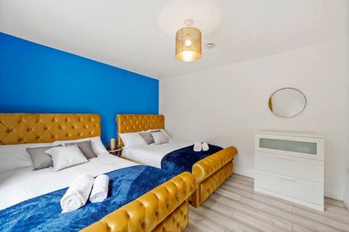 1 dormitorio con 2 camas y pared azul en Sleeps 5 - Large Garden - Wifi en Kent