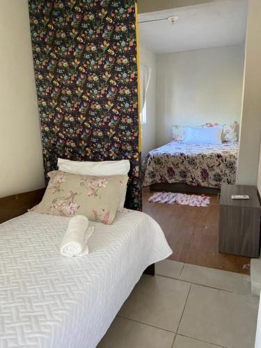 a bedroom with two beds and a floral wall at Casa da Vila Pousada in Três Coroas